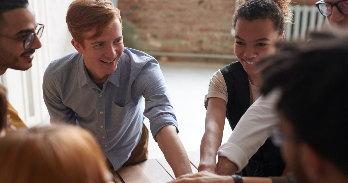 A group of people smiling and collaborating to convey positive teamwork and collaboration